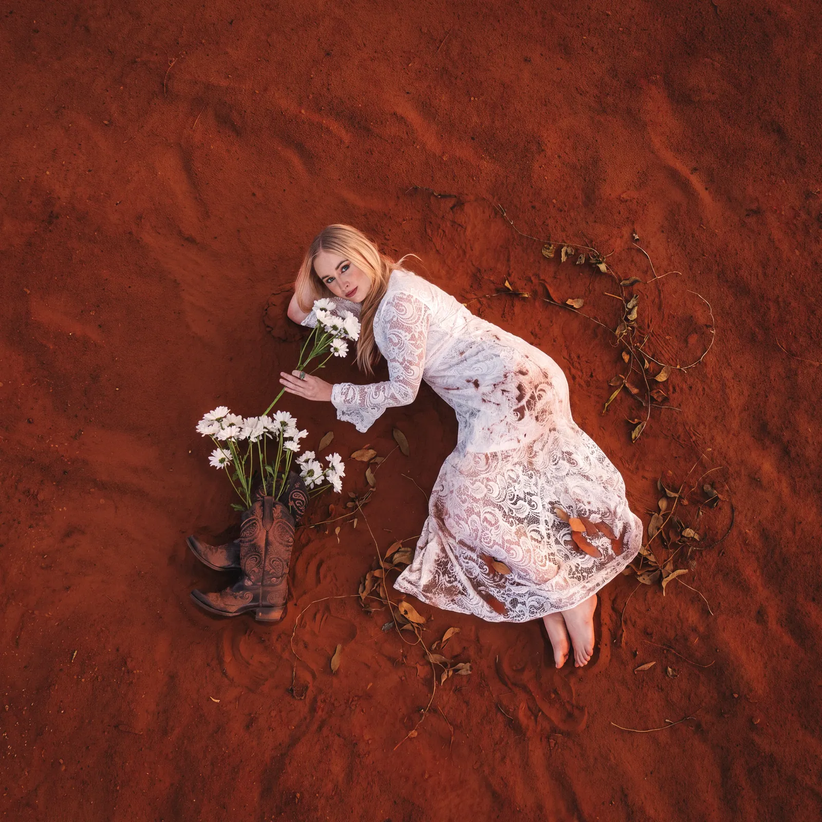 Melanie Dyer lying among daisies on red earth